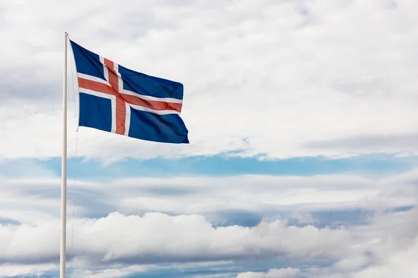 stock image Iceland flag waving with wind against blue sky with clouds