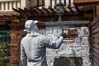 Boya işçisi duvarlara altlık boyası ekliyor ve yenileme aşamasındaki konut binasında paten olarak kullanılıyor.