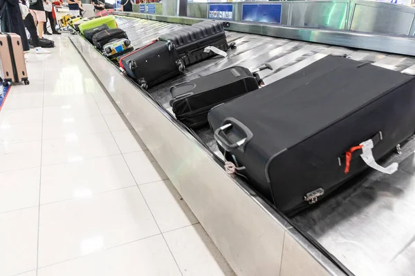 Baggage luggage at airport arrival carousel with passengers patiently awiating to claim theirs