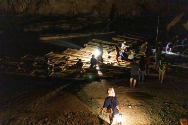 MAE HONG SON, THAILAND, 10 Mart 2023: Tham Nam Loc parkındaki turistlere yol gösteren bir Shan rehberi geleneksel feneriyle mağara sisteminin içinde sallarla nehir kıyısına doğru yürüyor..