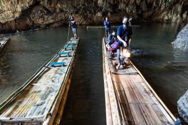 MAE HONG SON, THAILAND, 10 Mart 2023: Tham Nam Loc 'taki turistlere yol gösteren bir Shan rehberi geniş mağara nehir sistemi içindeki bambu sallarda geleneksel fener tutuyor..