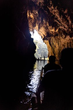 Sihouette 'deki turist, Tayland' ın Mae Hong Son bölgesindeki Tham Nam Lod mağaraları içindeki karanlık tünel nehrinin içinde bambu sallarla feribota bindi..