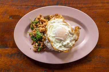 Prad Ka Pao 'nun genel manzarası. Tayland Steet yemekleri. Fesleğenli kızarmış domuz eti ve pilavlı sahanda yumurta. Tahta masada servis edilir..