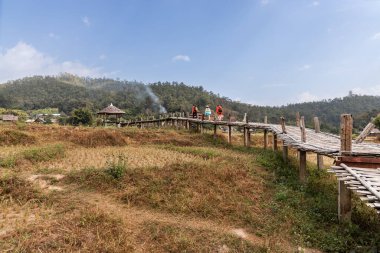 Buda bambu köprüsünde ya da Boon Ko Ku 'da yürüyen turistler pirinç tarlalarından geçerek küçük bir tapınağa kadar 800 metre uzunluğunda bambu yolu boyunca uzanırlar. Kuzey Tayland, Pai 'de turizm eğlencesi.