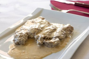 Simple serving portion of sliced beef steak with parmesan cheese gravy, an Italian delicay in Tuscany, Italy