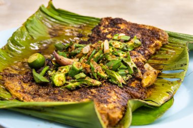 Malezya 'da muz yaprağının üzerinde bamya sebzeli baharatlı ızgara vatoz balığı ve popüler sokak yemekleri.
