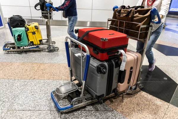 Traveller pushing trolley with luggages and bags in airport terminal after arrival