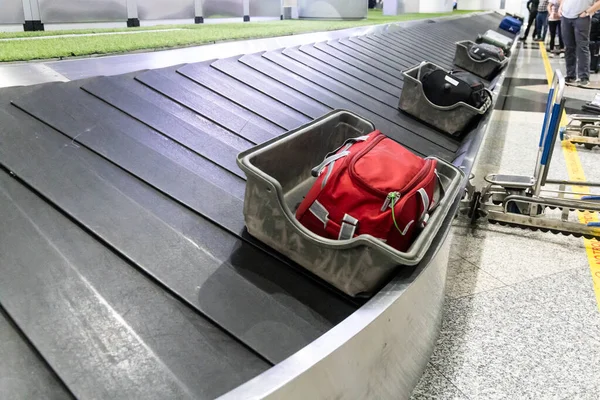 柔らかく壊れやすい袋の荷物は乗客のコレクションのための空港のコンベヤー ベルトに荷を積まれる前に保護容器に置かれます — ストック写真