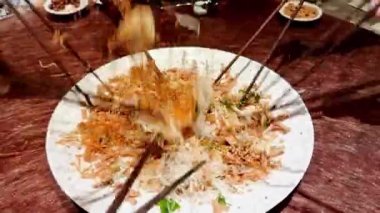 Çin Yeni Yıl yemeği kutlamalarında insanların birbirine karıştırıp fırlatması ve Yee Sang 'ın şarkı söylemesi, şans getirdiğine inanılıyor..