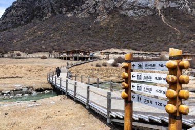 Garze Tibet Özerk Bölgesi 'ndeki Yading Doğa Koruma Alanı' ndaki sahil yolu Luorong Çayırı 'nda nefes kesici. Yön işaretleri Çince ve İngilizce çevrilmiştir.