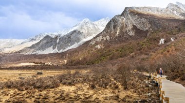 Hiker hiking in the scenic and breathtaking Yading nature reserve Luorong Pasture, located in Garze Tibetan Autonomous Prefecture, Sichuan, China clipart