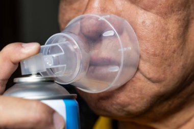 Yüksek rakımlı dağ bölgesindeki teneke kutudan oksijen soluyan yaşlı Asyalı adamın yakın çekimi.