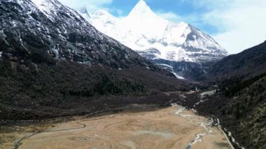 Arka planda Yangmaiyong Dağı, Garze Tibet Özerk Bölgesi, Sichuan, Çin 'de yer alan Yading doğa koruma alanı Luorong otlağının insansız hava aracı görüntüleri.