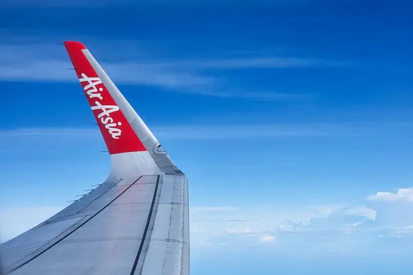 Stock image AirAsia is leading airline operating primarily in the Asia. Featured here closeup of the AirAsia logo imprinted on its wing tip against beautiful blue sky