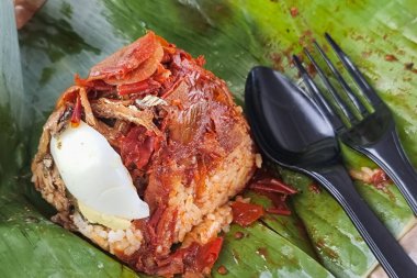 Nasi lemak bungkus 'un sade otantik servisi, hindistan cevizi sütüyle pişirilmiş pirinç ve muz yaprağına sarılmış sambal biberi, ançüez ve yumurta.