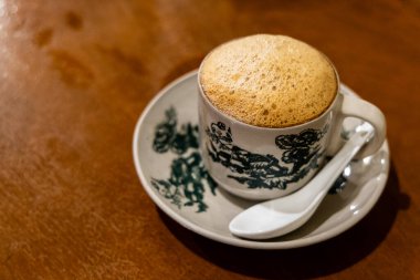 Popular traditional aromatic frothy coffee with milk served in retro cup and saucer at kopitiam in Malaysia