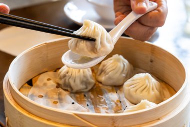Lokanta, Şangay 'ın popüler Xiaolongbao' sunu veya küçük ejderha hamur köftesini alıp bambu sepeti içinde restoranda yemek çubuklarıyla servis ediyor.