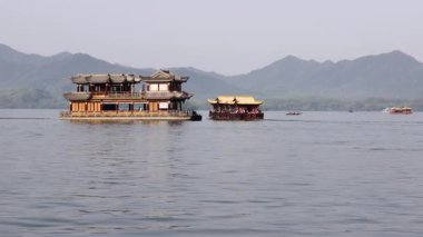 Sisli ve kasvetli bir sabahta Çin 'in batısındaki Hangzhou Gölü manzaralı göl gezisinde iki tekne kesişiyor.