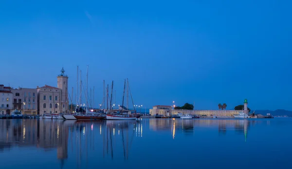 フランスのラ シオタ港での青い時間の状況 村の中心部の歴史的な建物とセーリングボートのマストは港の水に反映されています — ストック写真