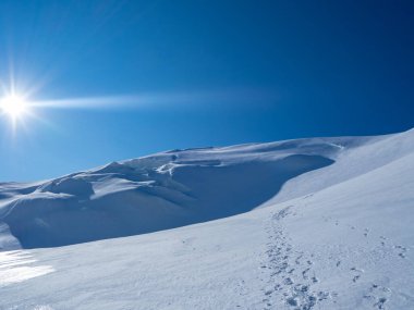 İsviçre 'nin Valais kentindeki Strahlhorn tepesinde güneşli bir sabah: Zirveye doğru giden kardaki ayak izleri.