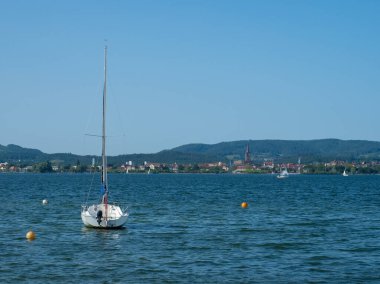 Almanya 'nın Iznang kasabasında, Constance Gölü' nün şamandırasında küçük bir yelkenli. Radolfzell şehrine doğru gölün üzerinden bak..