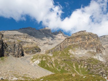 Haute Cime, İsviçre 'nin Valais şehrinde, Dent du Midi' de 3.000 metrenin üzerinde bir zirve. Yeşil çayırların arkasındaki kayalık dağın manzarası.