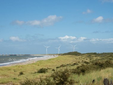Hollanda 'nın Zeeland bölgesi inanılmaz güzellikte bir kıyı manzarası sunar. Rüzgâr jeneratörleri ve Oosterscheldekering barajının önünde fırtına dalgalanması bariyeri olarak inşa edilmiş bir kumsal durumu.