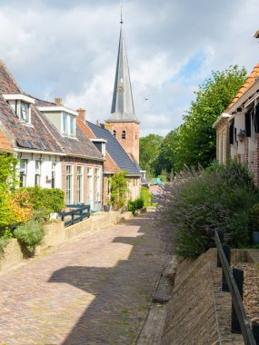 Holwerd, Hollanda, Batı Friesland 'da güzel bir köydür. Aile evleri ve köyün tuğla kilisesi olan bir mahalleden geçen bir caddenin durumu..