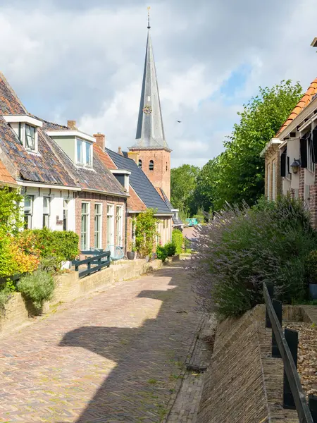 Holwerd, Hollanda, Batı Friesland 'da güzel bir köydür. Aile evleri ve köyün tuğla kilisesi olan bir mahalleden geçen bir caddenin durumu..