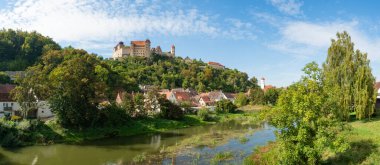 Woernitz nehrinin üzerinden Almanya 'nın Bavyera eyaletindeki tarihi Harburg kasabasına doğru, ormanın yukarısındaki ünlü şatonun manzarasını izleyin.