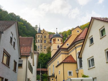 The village of Weissenstein in the Schwaebische Alb region, Germany, is situated in a shadowy valley. Situation of the village with the church and the castle under the forested slopes. clipart