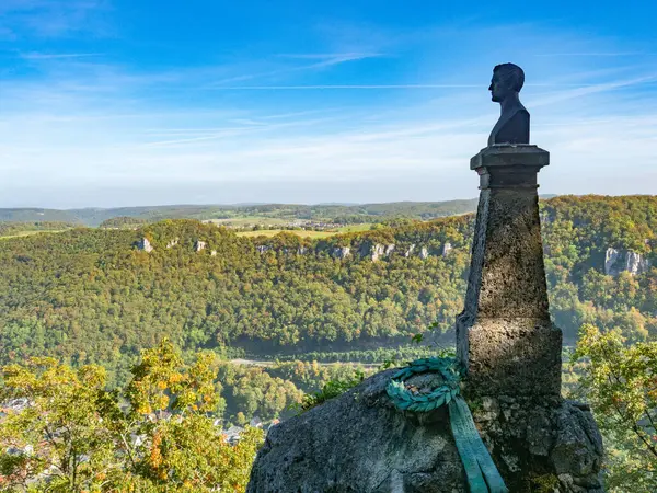 Schwaebische Alb dağının tepeleri, vadileri ve ormanlarıyla güzel bir manzara. Manzarayı izleyen eski bir heykel..