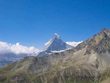 İsviçre 'nin ünlü Matterhorn zirvesine alışılmadık bir manzara, kayalık bir dağ sırtının arkasında. Zermatt 'tan Mettelhorn' a yükselişi izle.