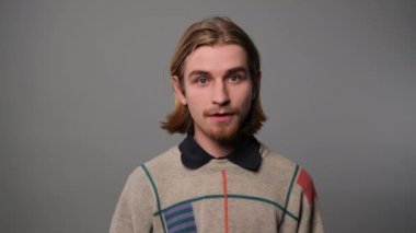 Garip görünen ve gri arkaplan üzerinde inkar eden bir adam.