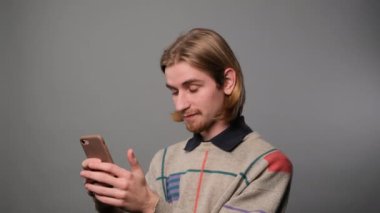 Gri arkaplan üzerinde cep telefonu kullanan adam