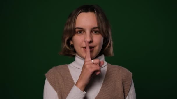 一个女人在绿色的背景上用手指捂住嘴唇 — 图库视频影像