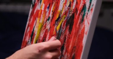 Man hand using palette knife for painting on canvas in studio