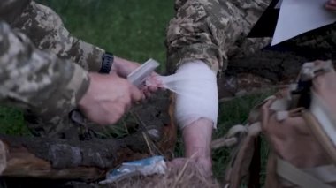Ukraynalı asker, Ukrayna 'nın Rus işgali sırasında meslektaşını savaş alanında bandajlıyor.