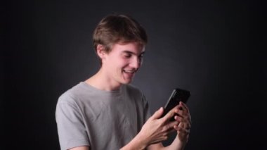 Sıradan giyinmiş, telefonda mesajlaşan ve tarafsız, siyah bir arkaplanda kahkahalara boğulan bir adam. Animasyon ifadeleri ve neşeli tavırları o anın tadını çıkarıyor..