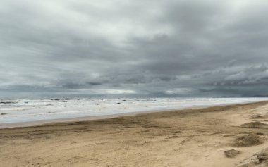 Beach view with rough sea, dramatic sky clipart