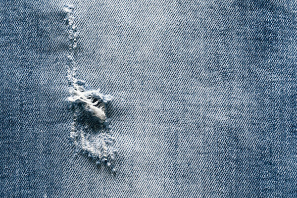 Close-up of hole in the jeans pants, texture background