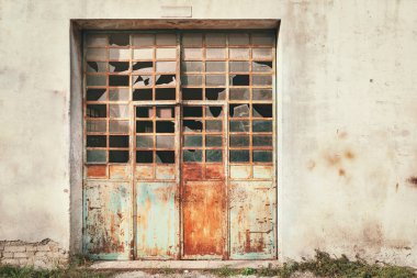 Kırık demir garaj kapısının önü, terk edilmiş bina detayları.