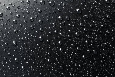 Su siyah bir yüzeye düşer, soyut bir arkaplan