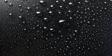 Su siyah bir yüzeye düşer, soyut bir arkaplan