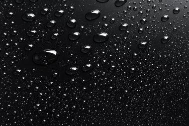 Su siyah bir yüzeye düşer, soyut bir arkaplan