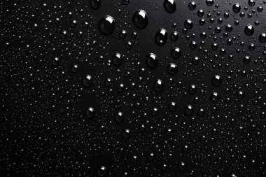 Su siyah bir yüzeye düşer, soyut bir arkaplan