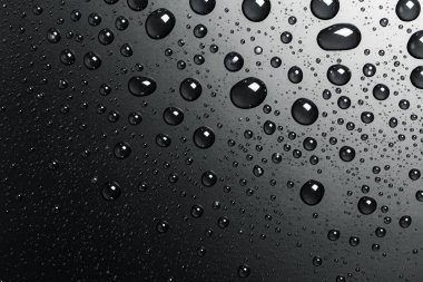 Su siyah bir yüzeye düşer, soyut bir arkaplan