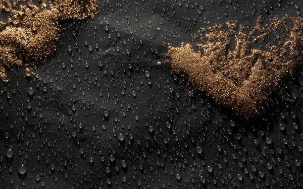 Su damlalarıyla siyah zemin üzerinde altın tozu. Üst görünüm