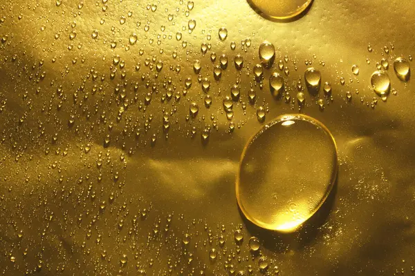 Yağmur damlalarıyla dolu taneli yüzey, altın su damlası.