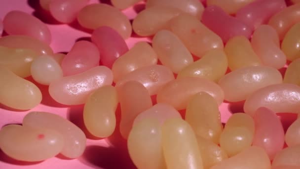 ゼリー豆品揃え混合物上のピンクの背景閉じるドル4Kショット選択的フォーカス — ストック動画